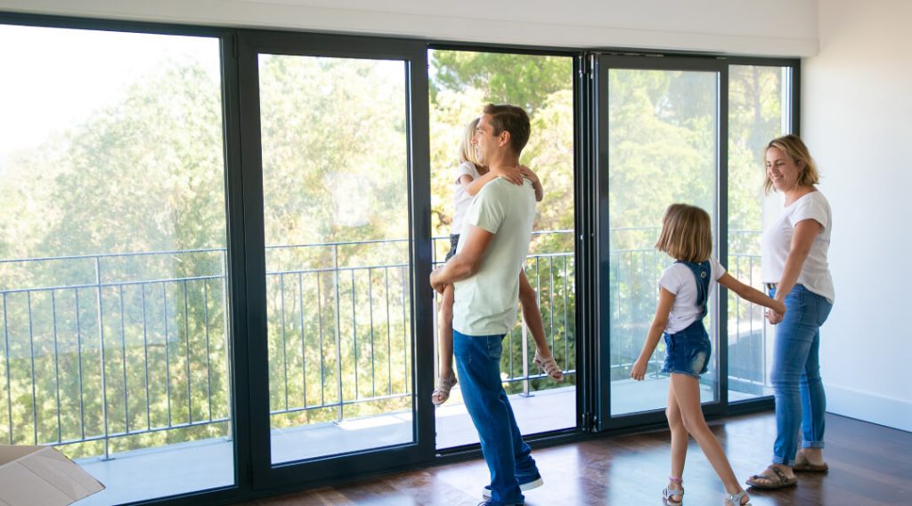 Famille dans une maison lumineuse avec grandes fenêtres modernes, illustrant les facteurs de prix pour remplacer des fenêtres au Québec